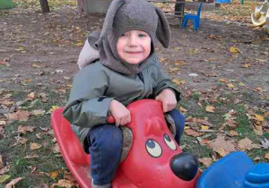 Franek pozuje do zdjęcia kołysząc się na bujaku w ogrodzie przedszkolnym