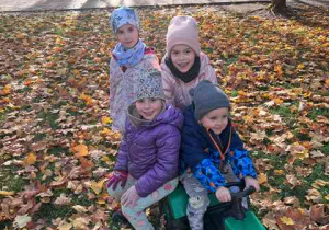 Dzieci w czasie zabawy w ogrodzie jadą traktorkiem i prowadzą obserwacje przyrodnicze