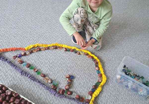 Układanie kompozycji z kasztanów oraz kamieni podczas ćwiczenia ciszy