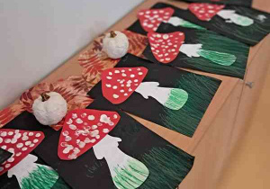 Prace plastyczne dzieci przedstawiające muchomory na czarnym tle