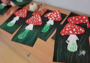 Prace plastyczne dzieci przedstawiające muchomory na czarnym tle