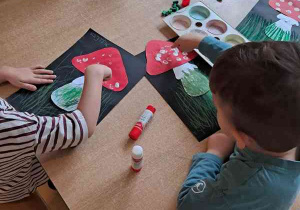 Dzieci stemplują białe kropki na kapeluszu muchomora placem zamoczonym w białej farbie