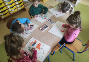 Dzieci kolorują kredkami figury geometryczne.