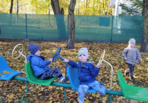 Chłopcy bawią się siedząc na krzesełkach z kierownicami