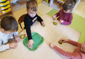 Dzieci wkładają wykałaczki w gruszkę, tworząc jeża