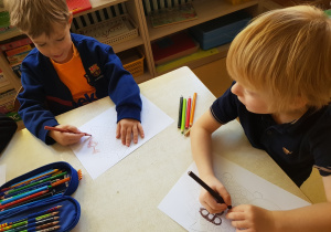 Chłopcy uzupełniają kartę pracy z jeżem