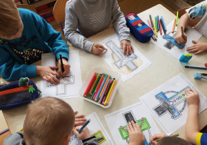 Dzieci kolorują kartę pracy przedstawiającą różaniec