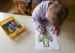 Dziewczynka koloruje kartę pracy przedstawiającą różaniec