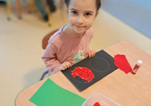 Nina siedzi przy stoliku i wykleja czerwone światło na sygnalizatorze