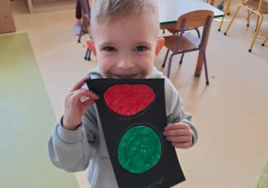 Kajtek pozuje do zdjęcia trzymając własnoręcznie zrobiony sygnalizator świetlny