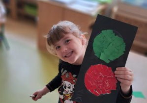 Wiktoria pozuje do zdjęcia trzymając sygnalizator świetlny