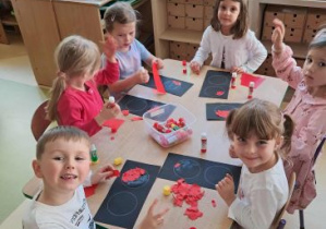 Dzieci siedzą przy stoliku i wykonują pracę plastyczną