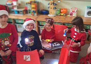 Dzieci na dywanie podczas rozpakowywanie prezentów od Mikołaja