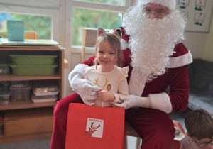 Dziewczynka pozuje do zdjęcia z Mikołajem i prezentem