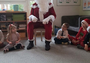 Dzieci siedzą w kręgu rozmawiają z Mikołajem