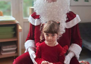 Dziewczynka pozuje do zdjęcia z Mikołajem i prezentem