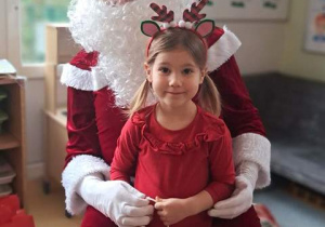 Dziewczynka pozuje do zdjęcia z Mikołajem i prezentem