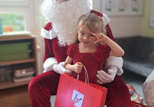 Dziewczynka pozuje do zdjęcia z Mikołajem i prezentem