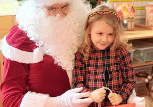 Dziewczynka pozuje do zdjęcia z Mikołajem i prezentem