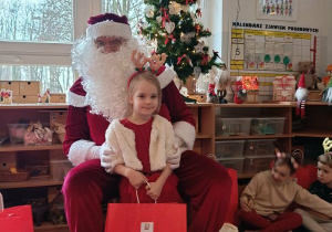Dziewczynka pozuje do zdjęcia z Mikołajem i prezentem