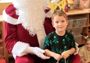 Chłopiec pozuje do zdjęcia z Mikołajem i prezentem