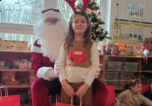 Dziewczynka pozuje do zdjęcia z Mikołajem i prezentem