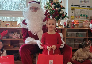 Dziewczynka pozuje do zdjęcia z Mikołajem i prezentem