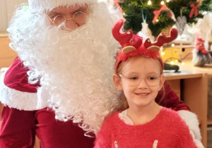 Dziewczynka pozuje do zdjęcia z Mikołajem i prezentem