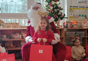 Dziewczynka pozuje do zdjęcia z Mikołajem i prezentem