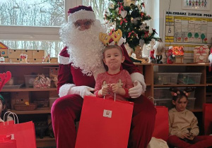 Chłopiec pozuje do zdjęcia z Mikołajem i prezentem