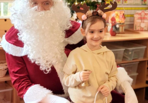 Dziewczynka pozuje do zdjęcia z Mikołajem i prezentem