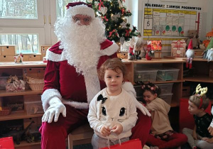 Dziewczynka pozuje do zdjęcia z Mikołajem i prezentem