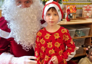 Chłopiec pozuje do zdjęcia z Mikołajem i prezentem