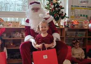 Dziewczynka pozuje do zdjęcia z Mikołajem i prezentem