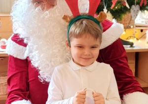 Chłopiec pozuje do zdjęcia z Mikołajem i prezentem