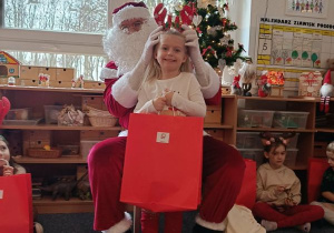 Dziewczynka pozuje do zdjęcia z Mikołajem i prezentem