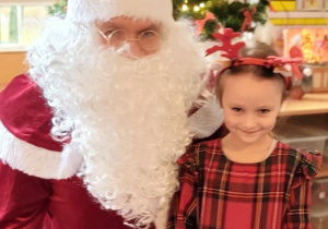 Dziewczynka pozuje do zdjęcia z Mikołajem i prezentem