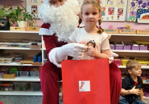 Dziewczynka pozuje do zdjęcia z Mikołajem i prezentem