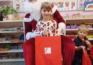 Dziewczynka pozuje do zdjęcia z Mikołajem i prezentem