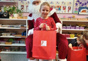 Dziewczynka pozuje do zdjęcia z Mikołajem i prezentem