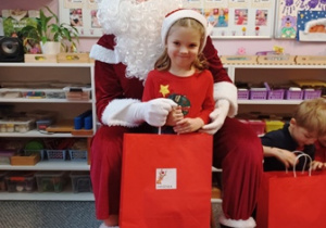 Dziewczynka pozuje do zdjęcia z Mikołajem i prezentem