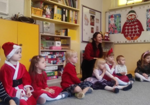 Dzieci z podziwem słuchają Mikołaja.