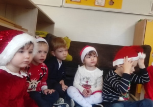 Dzieci siedzą w kręgu w oczekiwaniu na prezenty od Mikołaja.