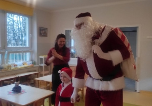 Chłopiec prowadzi Mikołaja do pozostałych dzieci.