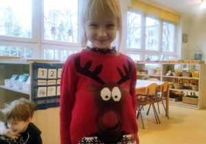 Dziewczynka w świątecznym sweterku czeka na Mikołaja.