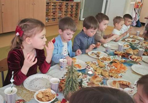 Dzieci siedzą przy wigilijnym stole