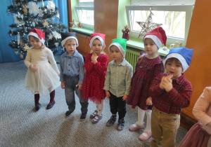 Dzieci w mikołajowych czapkach podczas świątecznego występu