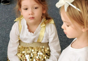 Dziewczynki siedzą na dywanie