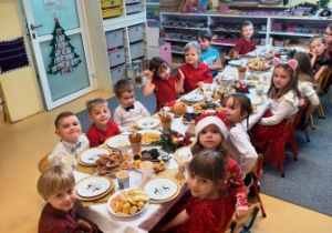 Dzieci siedzą wspólne przy wigilijnym stole