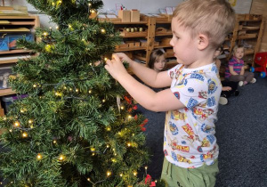 Chłopiec wiesza ozdobę na choince